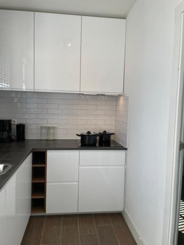 Una cocina con gabinetes blancos y encimera. en Vakantiehuis in het hart van Medemblik, en Medemblik