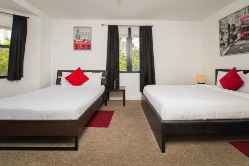 two beds in a room with red pillows at Apartments in the Heart of Miami - Port of Miami / Miami Airport in Miami