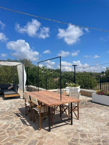a wooden table and chairs on a patio at Dimorae Camà in Cisternino