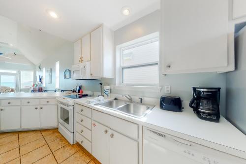 a kitchen with white cabinets and a sink and a window at A Sea Of Sand & Stars in St. George Island
