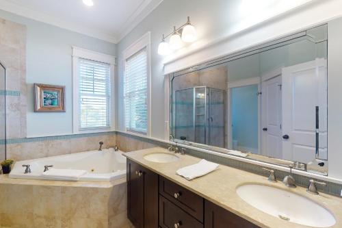 La salle de bains est pourvue de 2 lavabos, d'une baignoire et d'un grand miroir. dans l'établissement Le Reve, à Île Saint Georges