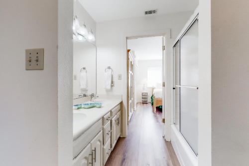 a white bathroom with a sink and a mirror at Our Thyme in St. George Island