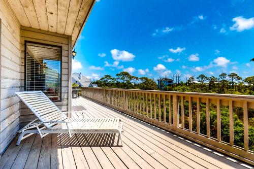 a deck with a white chair on a house at Our Thyme in St. George Island