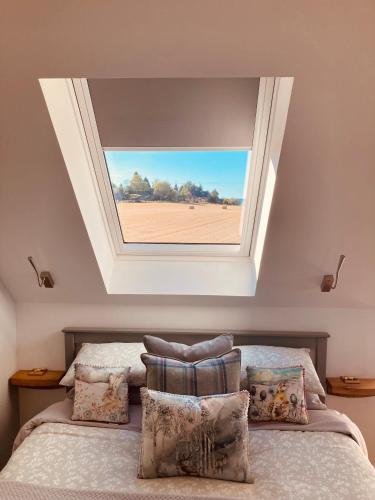 a room with a bed with a window above it at 'Wardlaw View' Luxury studio apartment with stunning view in Kirkhill