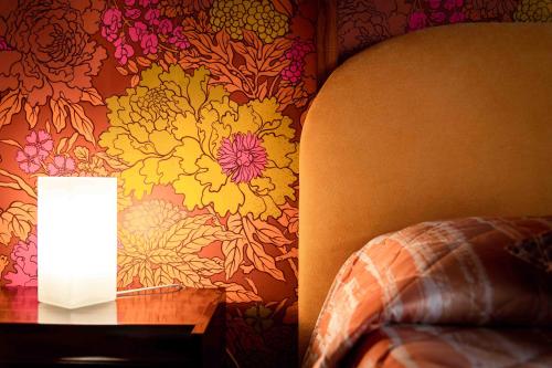 una lámpara en una mesa junto a una pared con flores en Tetide Home en Palermo