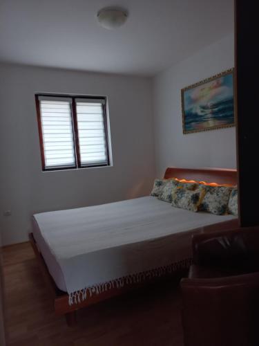 a bedroom with a large bed with two windows at Apartman Milic in Soko Banja