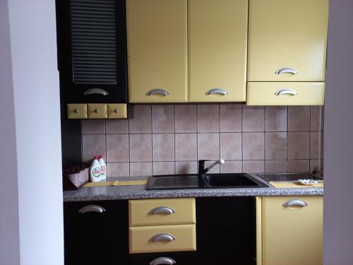a kitchen with yellow cabinets and a sink at Apartman Milic in Soko Banja