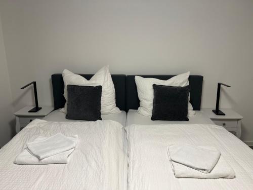 two beds with white sheets and black pillows at QUELLQUARTIER in Fulda