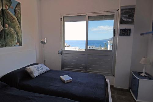 Un dormitorio con una cama y una ventana con un libro. en Apartamento en La Caleta El Hierro en Valverde