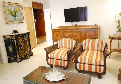 een woonkamer met 2 stoelen en een televisie bij Heraklion Center Boutique 3 Bedroom Apartment Penelope in Heraklion