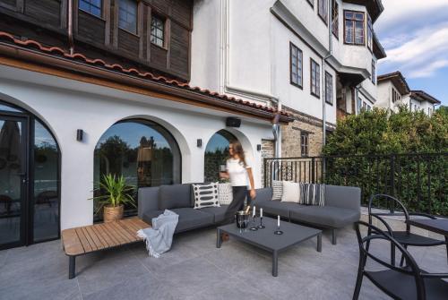 a woman standing on a patio with couches and tables at Bridges Residence in Veliko Tŭrnovo