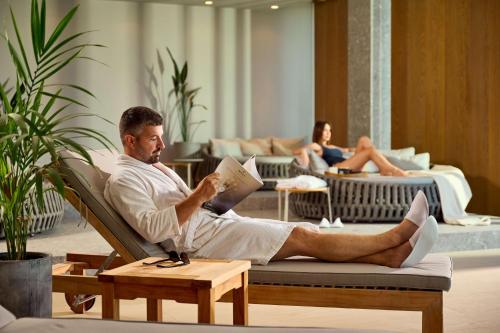 a man sitting in a chair reading a book at Radisson Blu Resort & Spa in Split