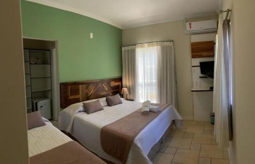 a bedroom with two beds and a window at Pousada Vô Jaques in Porto Belo