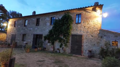an old stone house with a tree in front of it at Molino della Tuoma in San Quirico dʼOrcia