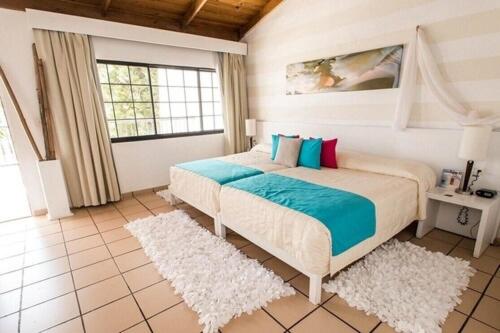 a bedroom with a bed with blue and pink pillows at BlueBay Villas Doradas Adults Only-All Inclusive in San Felipe de Puerto Plata