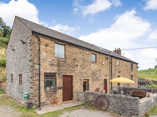 an old stone cottage with a wooden door and a patio at Peacock Cottage in Dove Holes