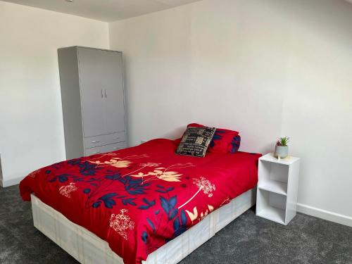 a bedroom with a bed with a red comforter at Layrek London 1 bedroom flat in London