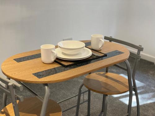 a wooden table with two cups and plates on it at Layrek London 1 bedroom flat in London