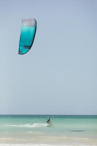 a person on a surfboard in the ocean with a kite at Cucu Hotel El Cuyo in El Cuyo