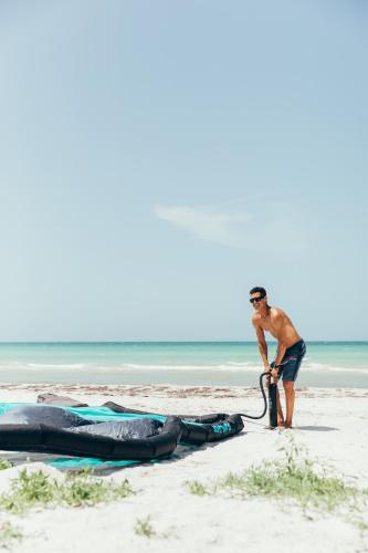 a man standing on a beach with a surfboard at Cucu Hotel El Cuyo in El Cuyo