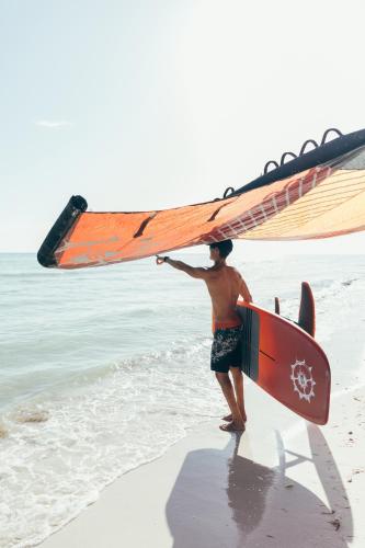a man holding a surfboard on the beach at Cucu Hotel El Cuyo in El Cuyo