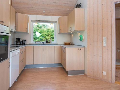 eine Küche mit Holzschränken und einem Fenster in der Unterkunft 6 person holiday home in Skjern in Halby