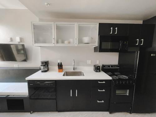 a kitchen with black cabinets and a sink at Sleepover Studio Apartments Downtown Springfield in Springfield