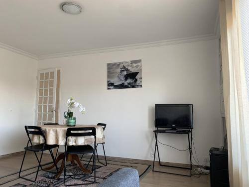 a living room with a table and a tv at Superbe T3 spacieux, lumineux et sans vis-à-vis in Vigneux-sur-Seine