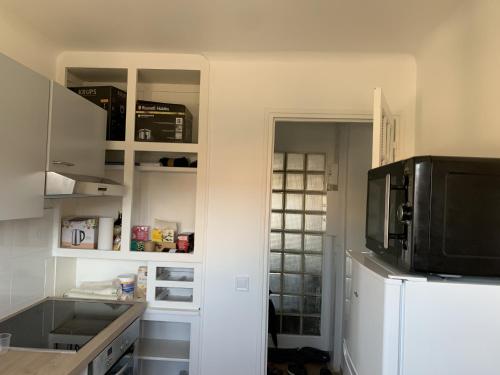 a kitchen with white cabinets and a microwave at Superbe T3 spacieux, lumineux et sans vis-à-vis in Vigneux-sur-Seine