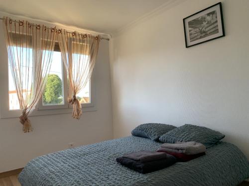 a bedroom with a bed with a blue blanket and a window at Superbe T3 spacieux, lumineux et sans vis-à-vis in Vigneux-sur-Seine