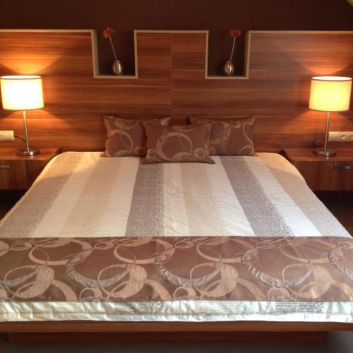a bedroom with a large bed with two lamps at Alfa Hotel in Győr