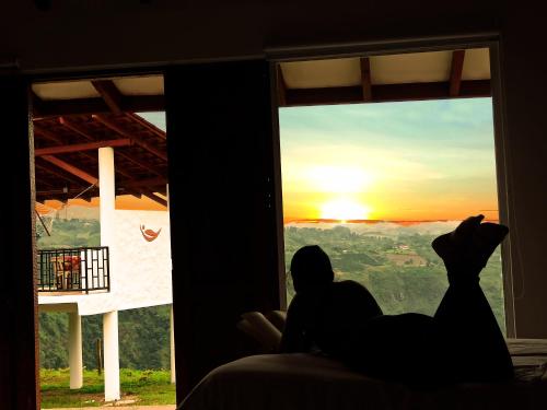 a person looking out of a window at the sunset at Hotel Kasama in San Agustín