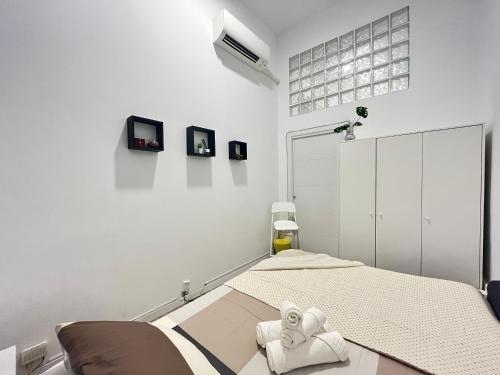 una camera da letto bianca con un letto e asciugamani di Ile Atocha Exterior Olivar a Madrid
