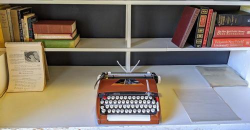 eine alte Schreibmaschine auf einem Regal mit Büchern in der Unterkunft The Andiron Seaside Inn & Cabins in Little River