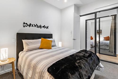 - une chambre avec un grand lit et un oreiller jaune dans l'établissement Academy Apartments, à Masterton