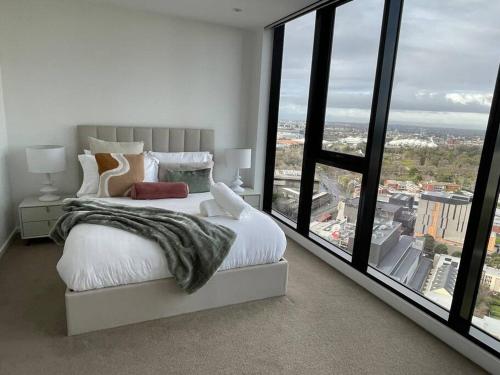 a bedroom with a large white bed and large windows at Lux 3 Bedroom Apartment in Southbank in Melbourne