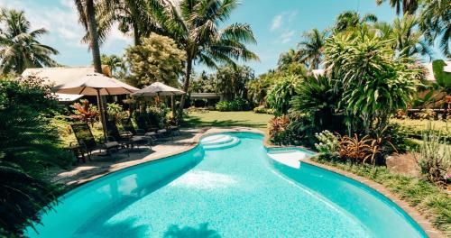 einen Pool in einem Resort mit Palmen in der Unterkunft Ikurangi Eco Retreat in Rarotonga