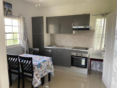 a kitchen with a table with chairs and a table and a kitchen with a stove at Sky Blue Residence in Lower Princeʼs Quarter