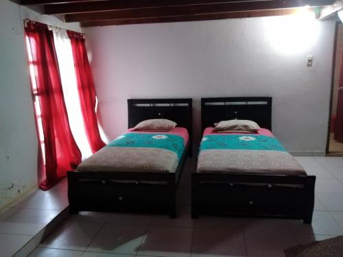 two beds in a room with red curtains at Phandy in Santa Veronica