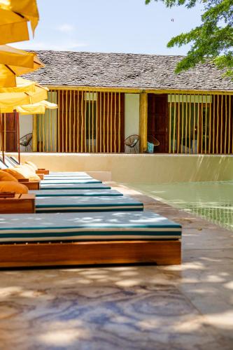 a row of lounge chairs and umbrellas next to a pool at Café Jeri Hotel - Adults Only in Jericoacoara