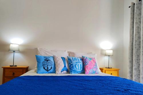 a bed with blue and white pillows on it at Sirena Village in São Miguel do Gostoso