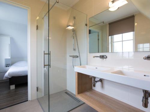 y baño con lavabo y ducha. en Beautiful villa with jacuzzi in a luxury holiday park on the Tjeukemeer, en Delfstrahuizen
