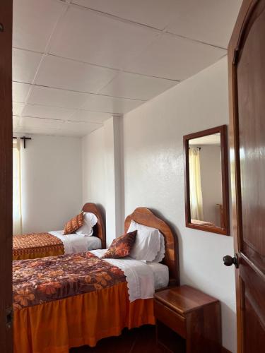 a bedroom with two beds and a mirror at Hospedaje Familiar Laos in Oxapampa