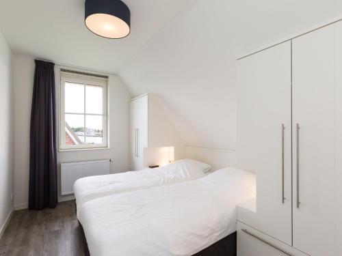 Habitación blanca con cama y ventana en Beautiful villa with jacuzzi in a luxury holiday park on the Tjeukemeer, en Delfstrahuizen