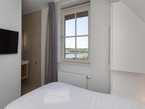 una camera con un letto bianco e una finestra di Beautiful villa with wellness in a holiday park on the Tjeukemeer a Delfstrahuizen
