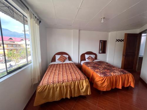 two beds in a room with a window at Hospedaje Familiar Laos in Oxapampa