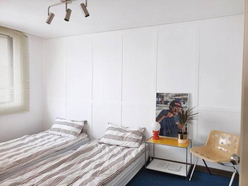 1 dormitorio con 2 camas, mesa y silla en [ COM,A stay] Hongdea St 5min / 3room, en Seúl