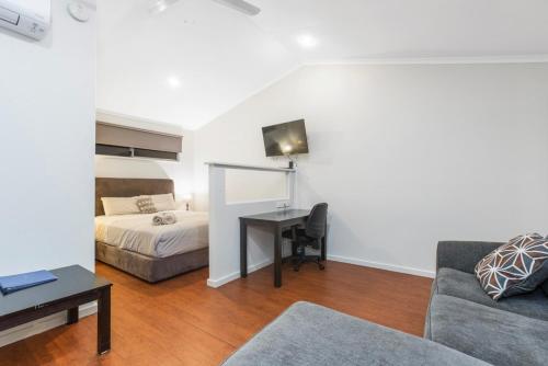a living room with a bed and a desk in a room at Aspen Karratha Village in Karratha