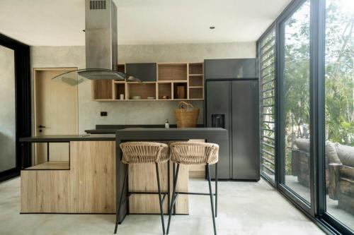 a kitchen with a counter with stools and a refrigerator at Villa Xuncari en el corazón de la selva Tulum in Tulum