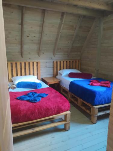 two beds in a room with wooden walls at Chalet de Liz in Guatapé